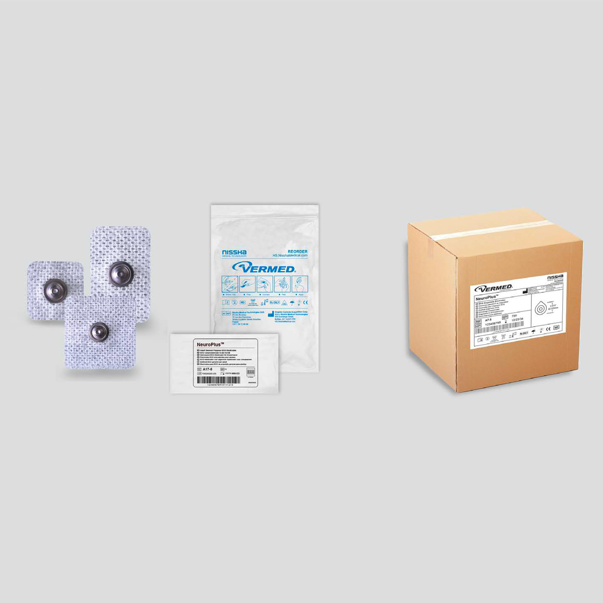 Kolme EKG-elektrodia, niiden pakkaus, ohje ja ruskea pahvilaatikko, joissa Vermed-etiketti.