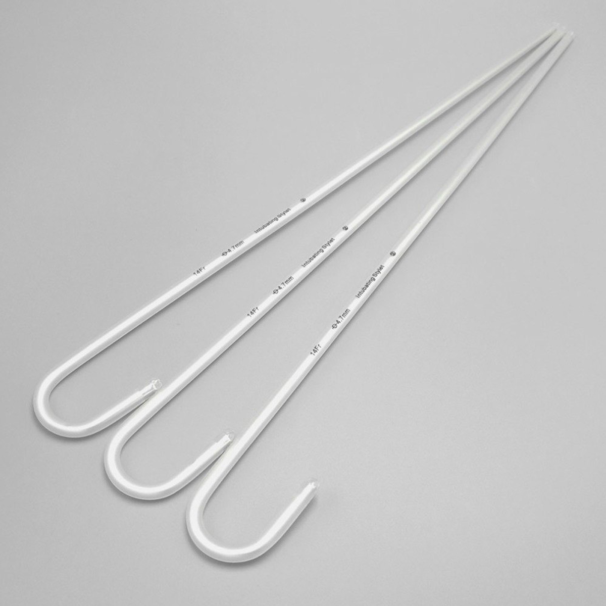 Kolme valkoista U-koukkuista muovitankoa harmaalla taustalla.