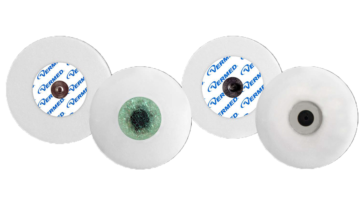 Neljä erilaista pyöreää EKG-elektrodia valkoisella taustalla, osa niistä merkitty Vermed-logolla.