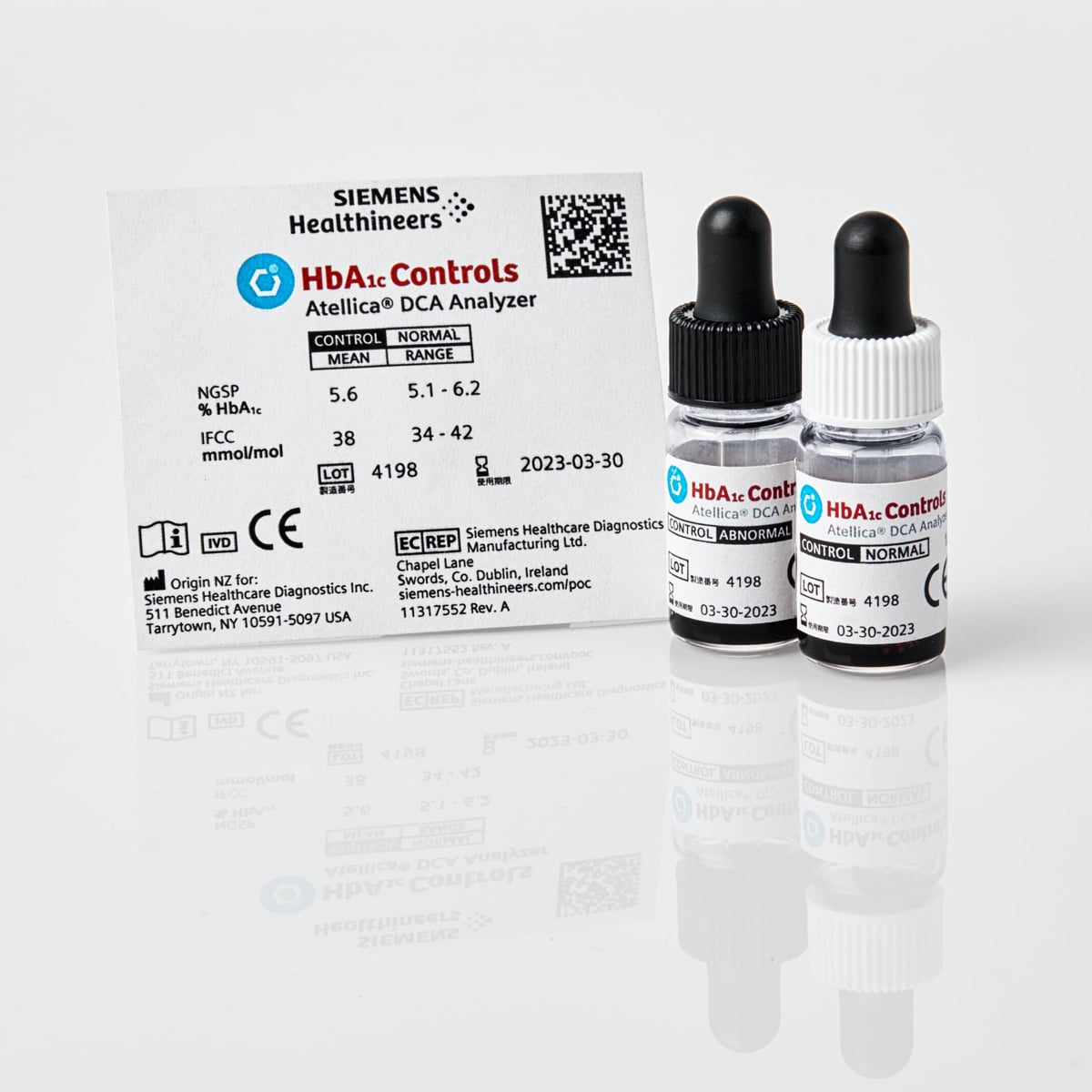 Kaksi pientä näytepulloa ja Siemens HbA1c Controls -selite Atellica DCA Analyzer -testiin valkoisella taustalla.
