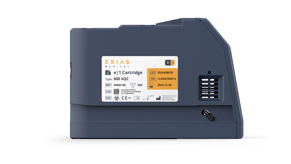 Harmaa EXIAS Medical e|1-kasetti, jossa näkyvissä tuotelappu, eränumero, sarjanumero ja viimeinen käyttöpäivä.